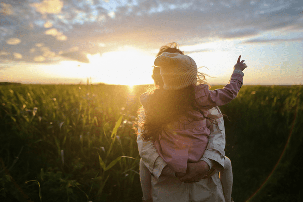 Silhouettes of a woman and child in a field at sunset, enjoying the beautiful evening.