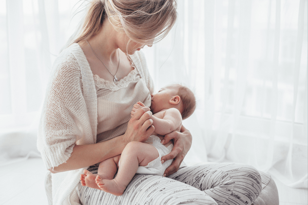 A mother nurturing her baby with love, breastfeeding in a serene white room.